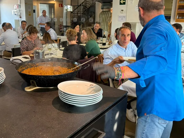 Cocinero de El Arroz de LaTomasa sirviendo la paella a un comedor lleno en una comida de grupo