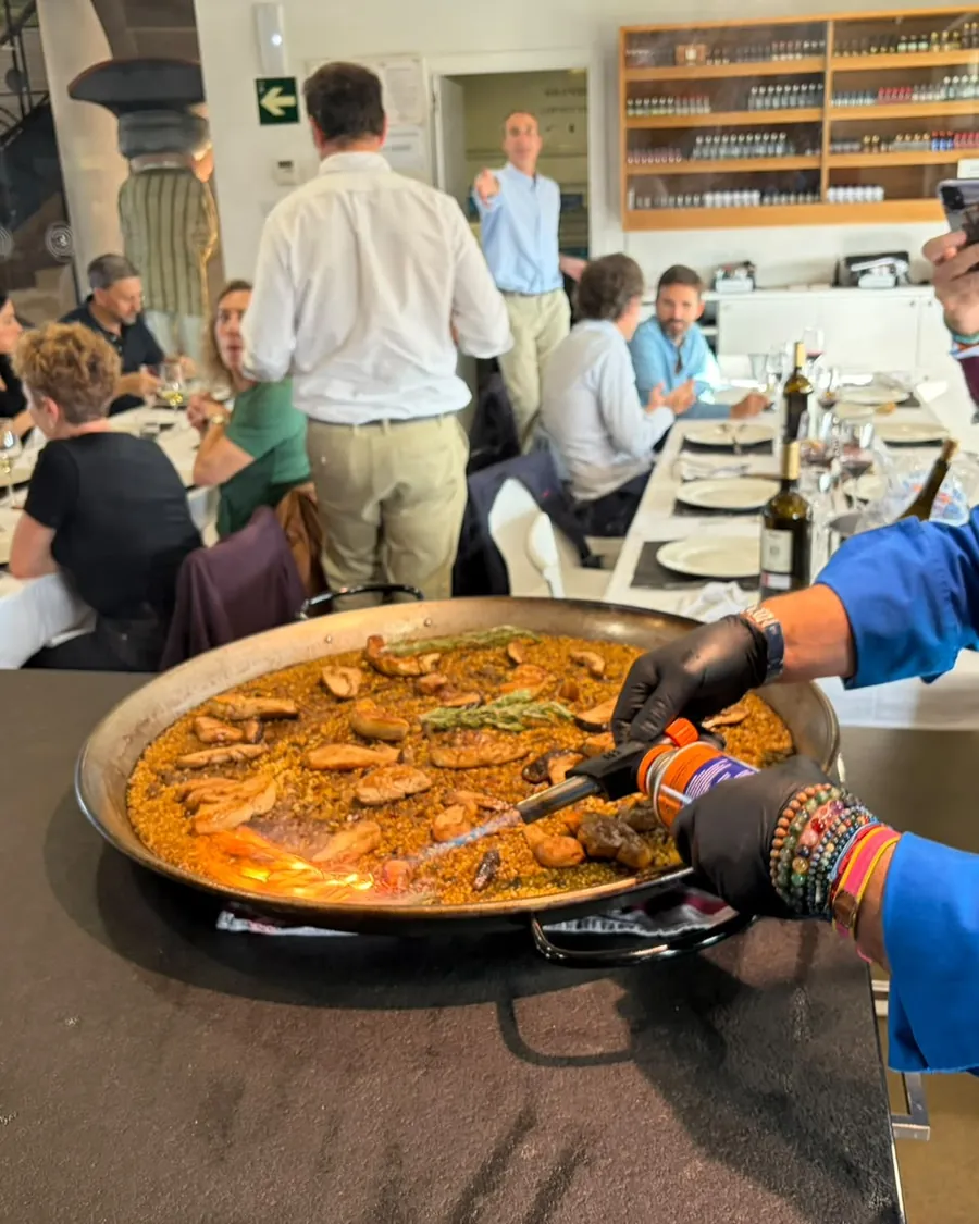 Cocinero de El Arroz de LaTomasa dando el toque final al soplete a una paella delante del comedor