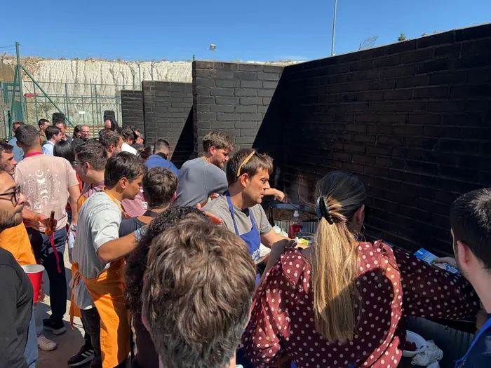 Grupo de una empresa con delantales cocinando su paella en el paellero durante un teambuilding